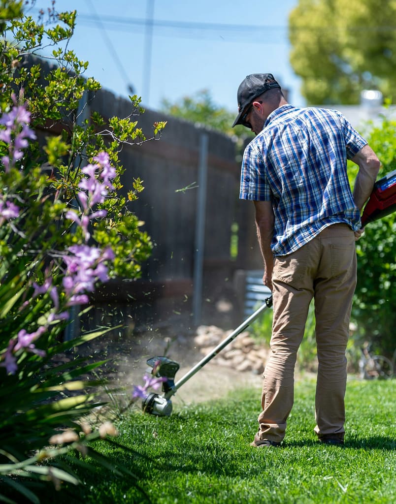man in check shirt trimming lawn